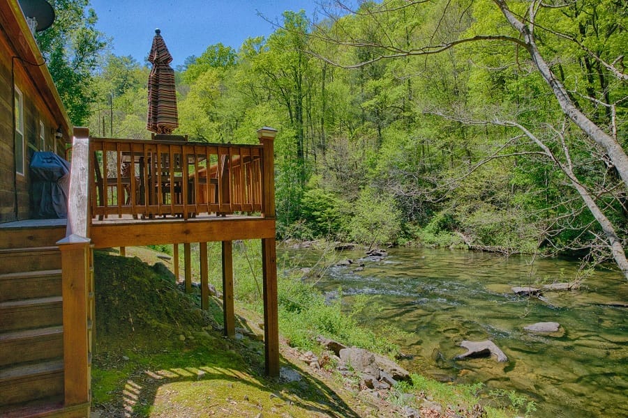 A wooden porch overlooking the Cheoah River and forest at Historic Tapoco Lodge.