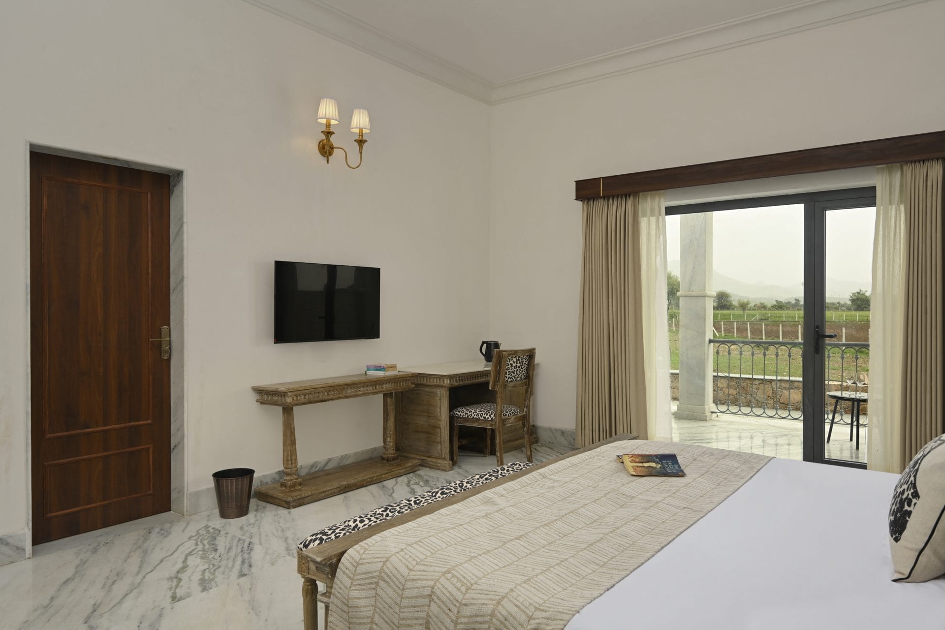 Deluxe room with king bed, console desk, and open balcony door