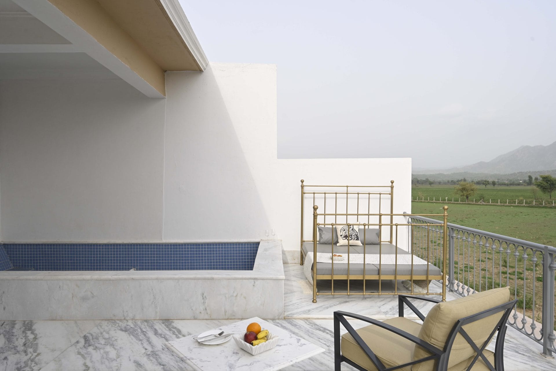 Marble terrace with plunge pool, daybed, and armchair looking over farmland