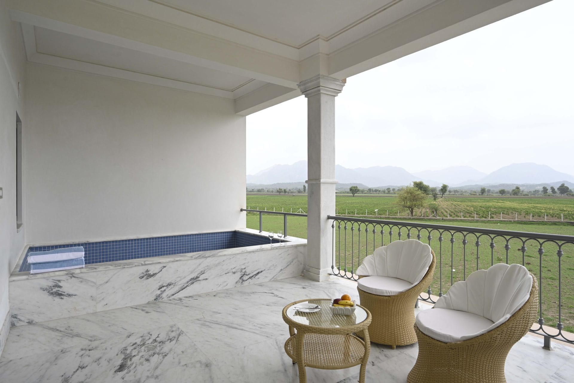 Covered suite terrace with plunge pool, wicker chairs, and a view of farmland and mountains