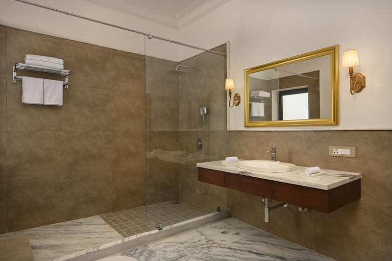 Deluxe bathroom with glass shower, marble vanity, and gold-framed mirror