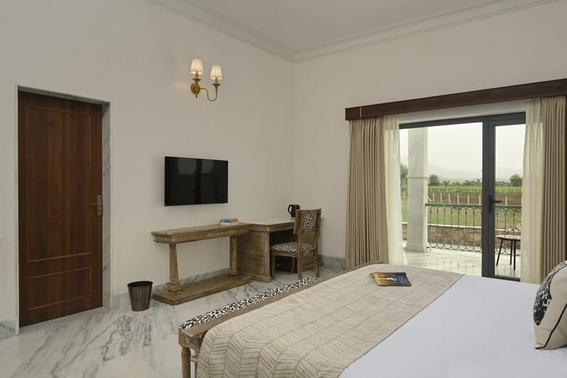 Deluxe room with king bed, console desk, and open balcony door