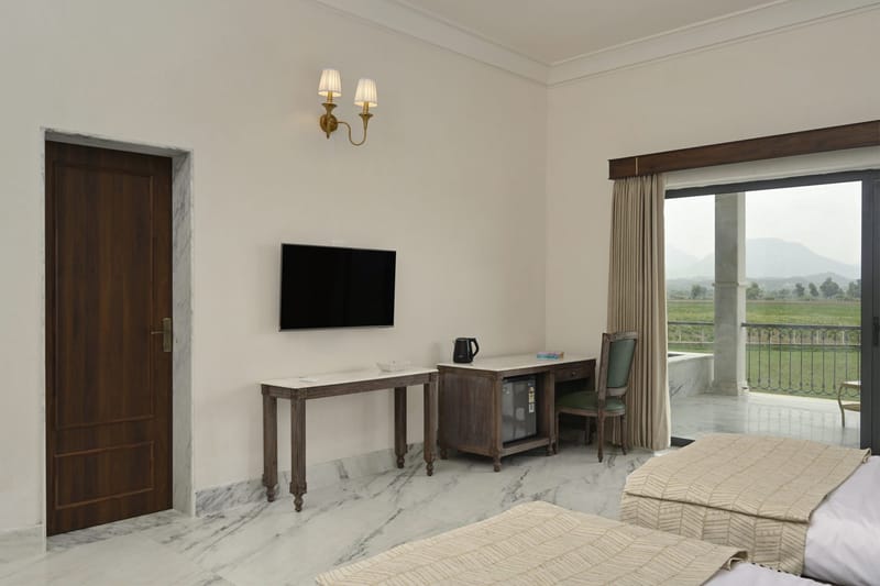 Deluxe room seen from the bed towards the desk and open balcony