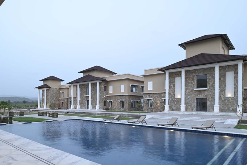 Pool with loungers in front of the stone facade, hills in the distance at dusk