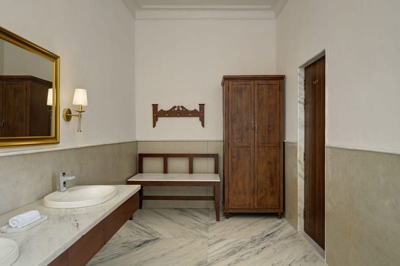 Suite bathroom with marble basin, wooden cabinet, and gold-framed mirror