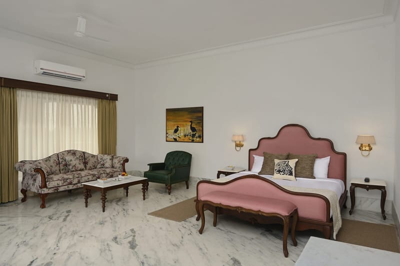Suite bedroom with king bed, floral sofa, and green armchair
