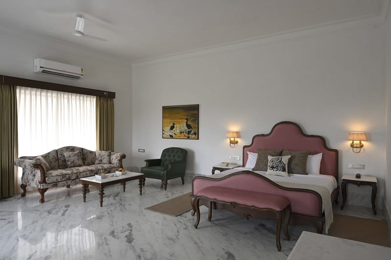 Suite bedroom seen from the sitting area, with bed and framed bird print