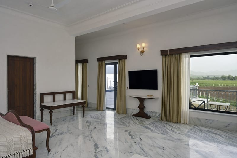 Suite lounge with wall-mounted TV, console, and glass door to the balcony