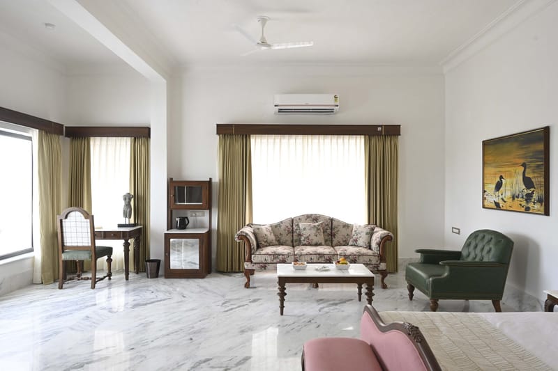 Suite sitting area with sofa, marble coffee table, and green armchair