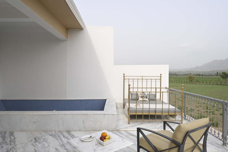 Marble terrace with plunge pool, daybed, and armchair looking over farmland