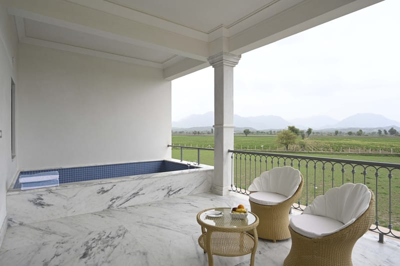 Covered suite terrace with plunge pool, wicker chairs, and a view of farmland and mountains