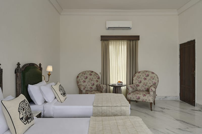 Floral armchairs and a side table by the window of a Twin Bed Room