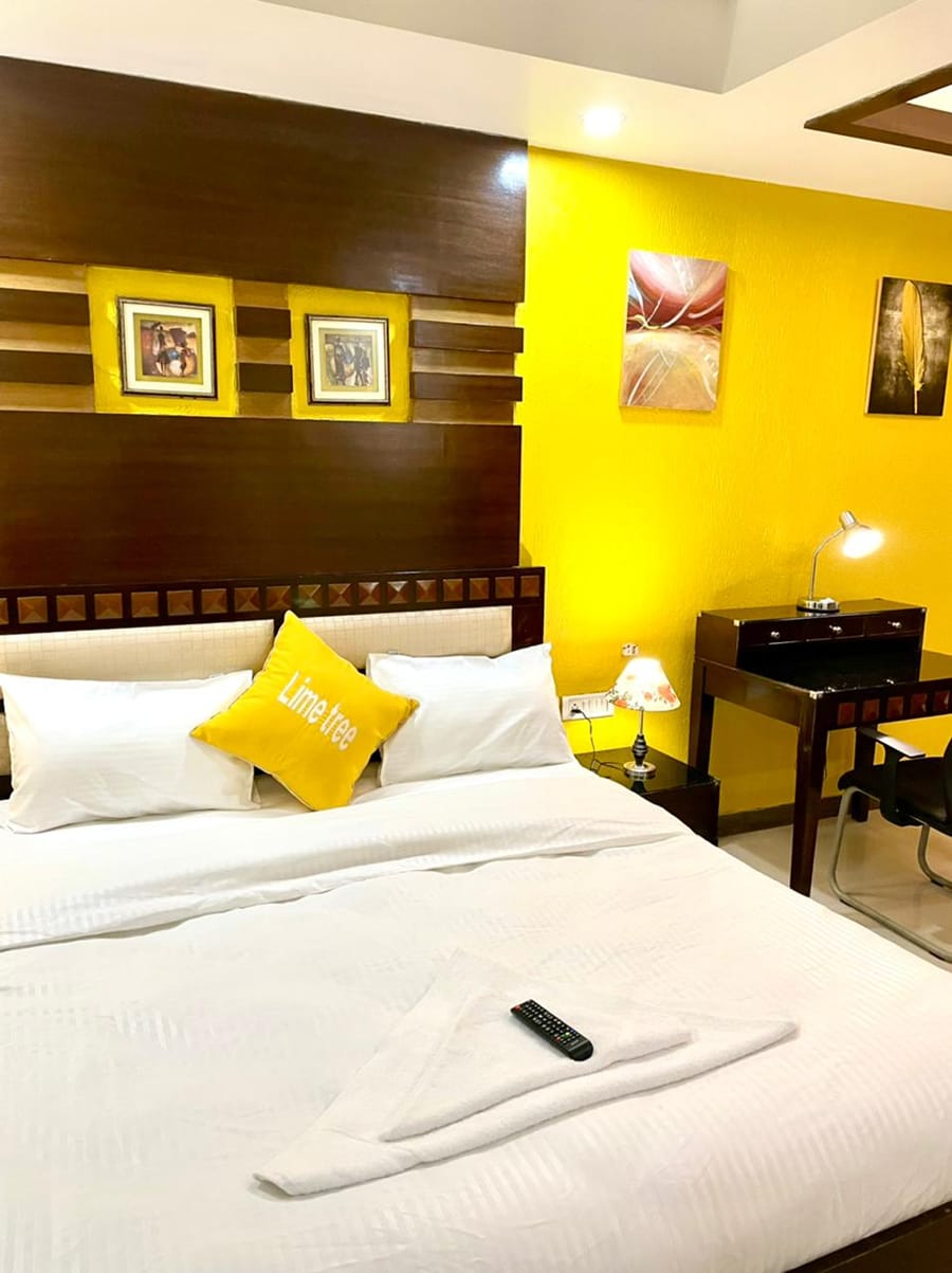 Bedroom with a double bed, yellow accent wall, desk and Lime Tree cushion at Lime Tree, Greater Kailash-2
