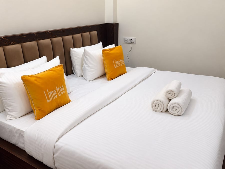 Deluxe Room king bed with an upholstered headboard at Lime Tree Hotel, Vrindavan