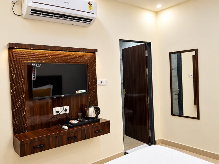 Room TV unit, kettle and mirror facing the beds at Lime Tree Hotel, Vrindavan