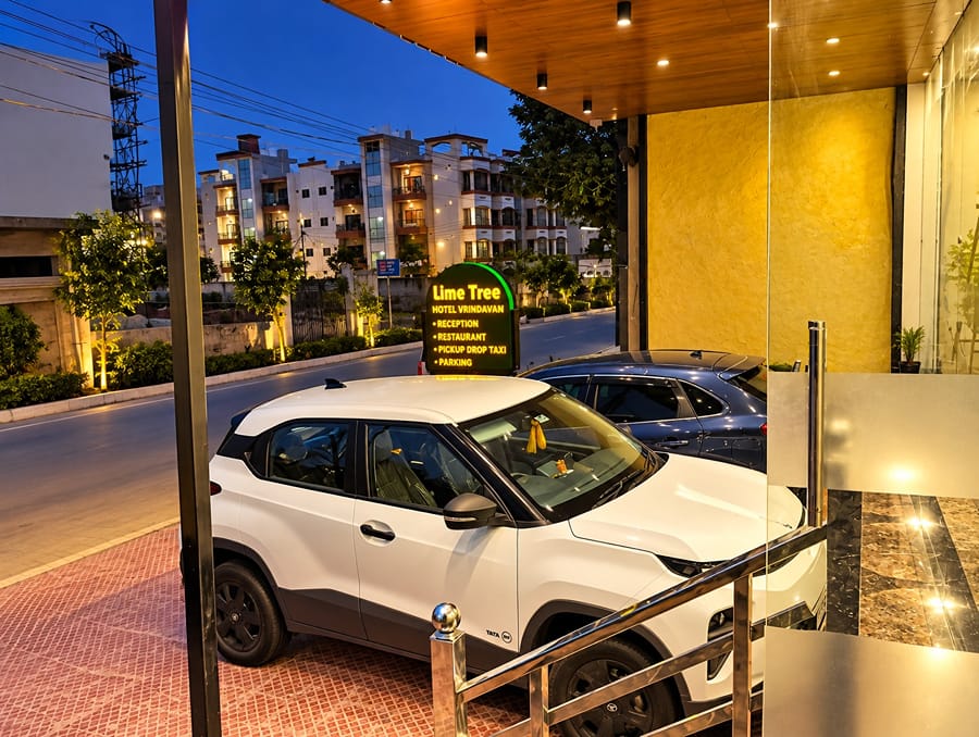 Car at the lit-up entrance of Lime Tree Hotel, Vrindavan at dusk