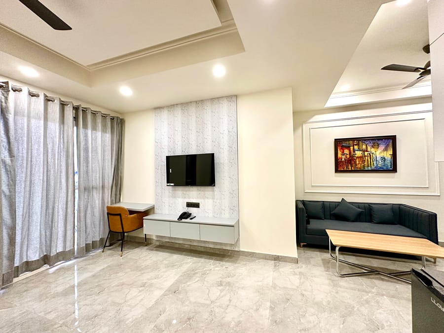 Living area with a wall-mounted TV, black sofa, coffee table and work desk at Street Studio by Lime Tree Hotels
