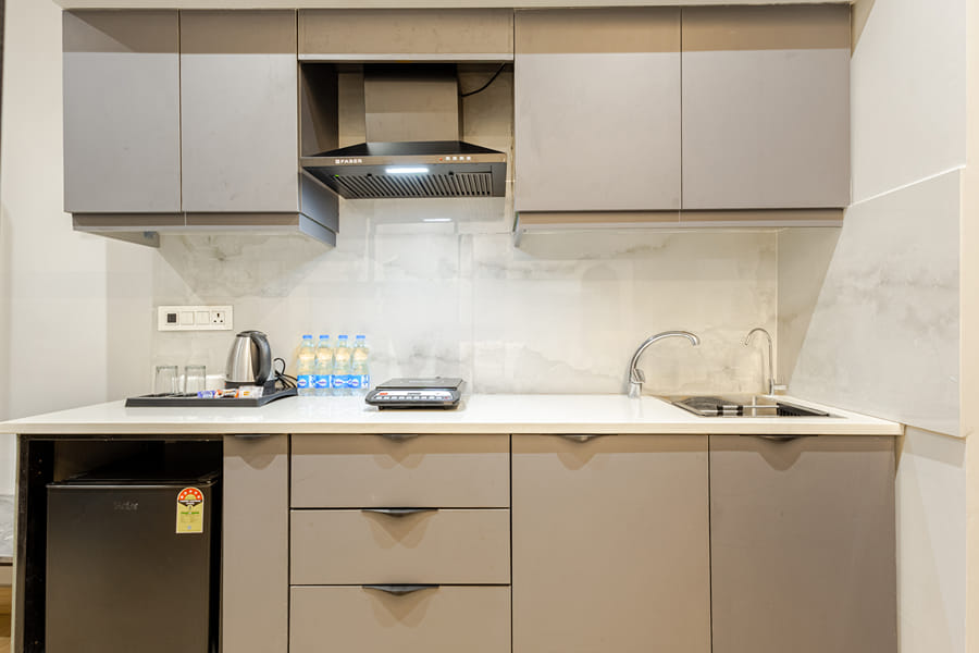 Kitchenette with grey cabinets, a chimney, a cooktop, a kettle and a fridge at Street Studio by Lime Tree Hotels
