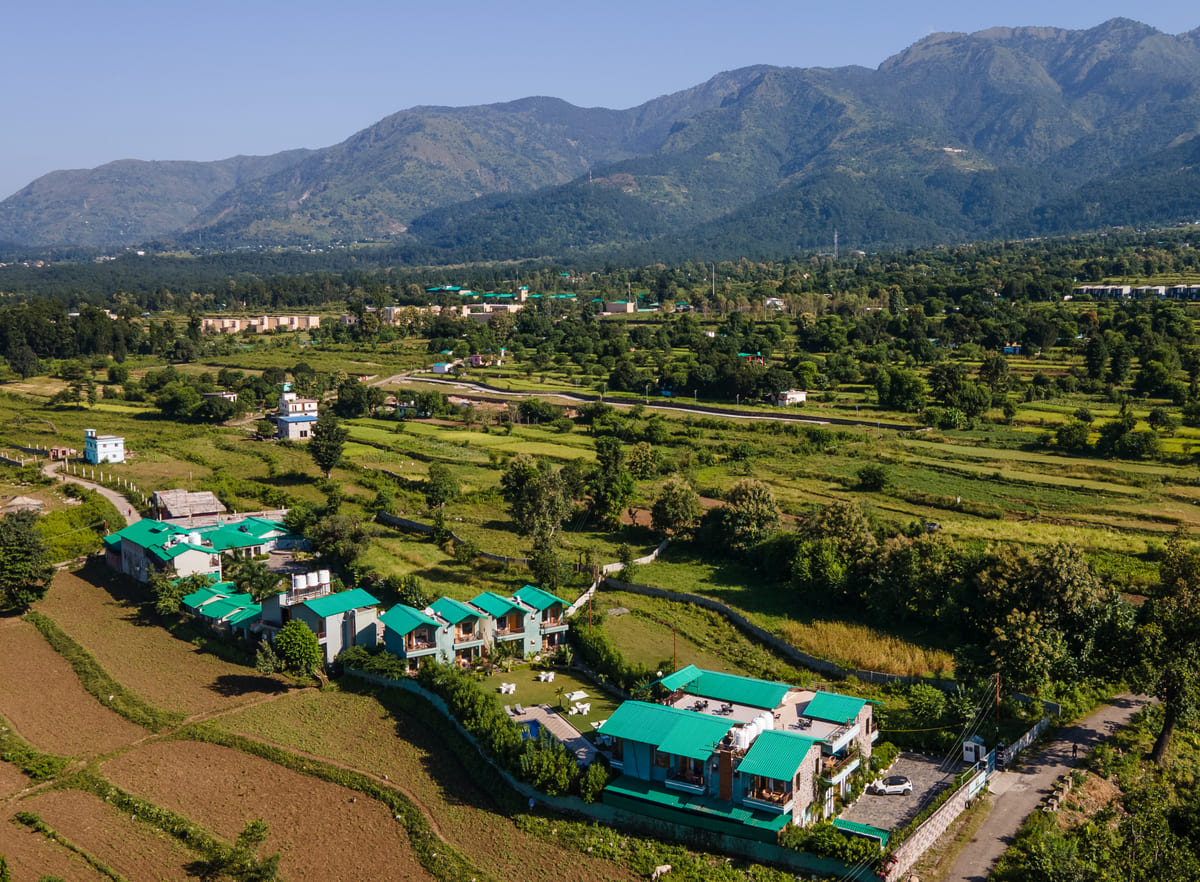 Aerial view of Corbett Nirvana cottages with farmlands and forest