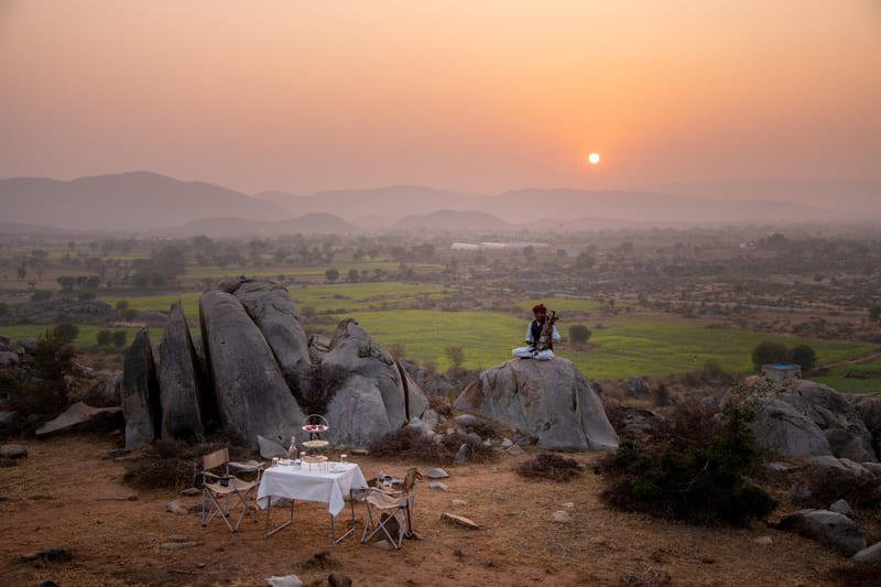 A single table dressed on a boulder, looking out over the fields at sunset