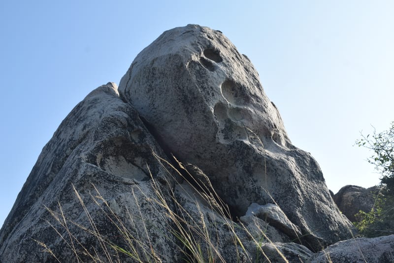 A granite boulder balanced on another above the scrub