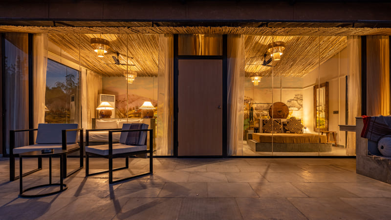 A Forest Bungalow veranda lit at dusk, opening onto the trees