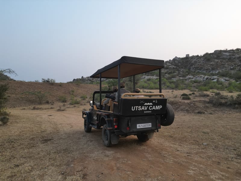 An image of a jeep parked amidst the rocky mountains - Utsav Camp Sariska