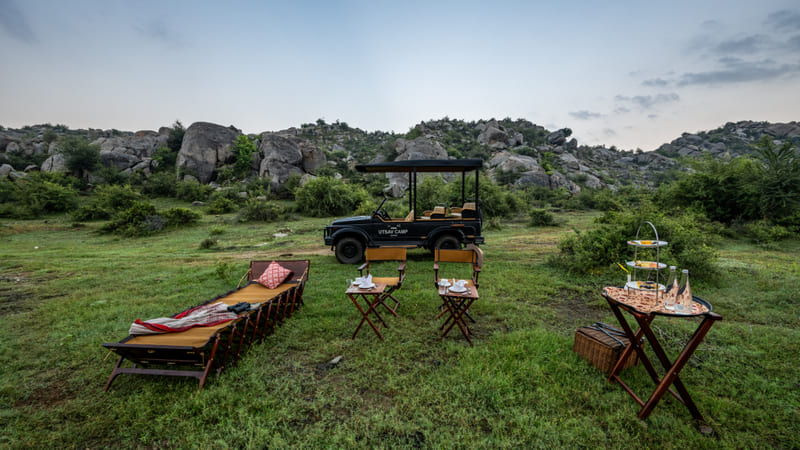 Loungers and a drinks table set on the grass among the boulders