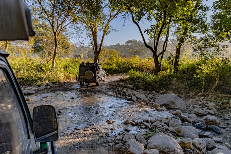 A safari jeep fording a rocky stream bed in the reserve