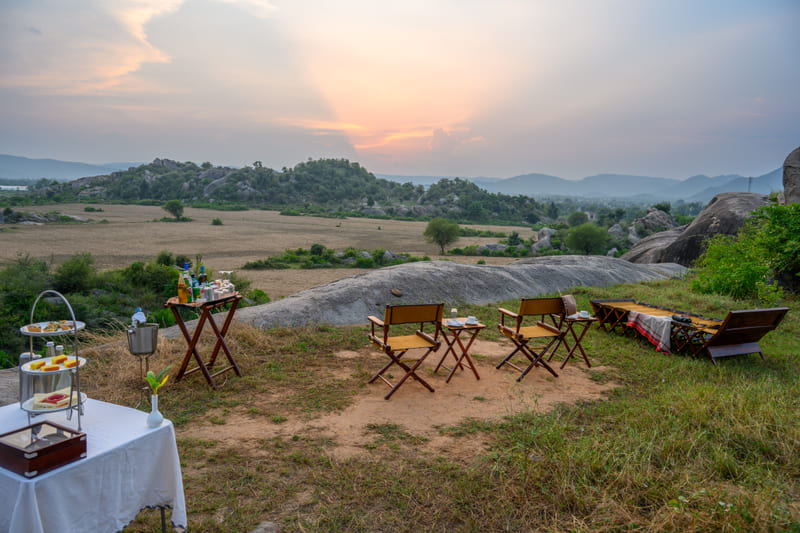A sundowner set out with chairs and a drinks table as the sun drops behind the boulders