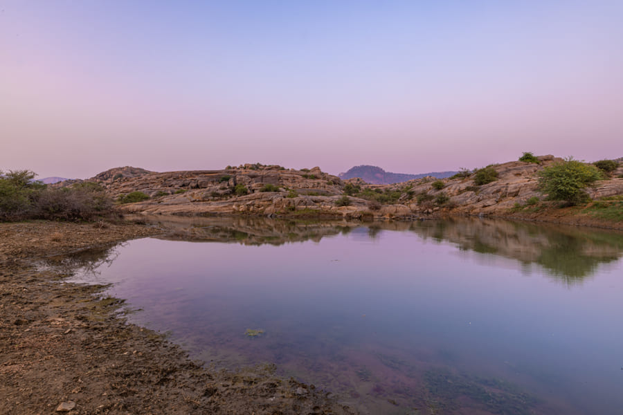 Still water among the boulders under a dusk sky