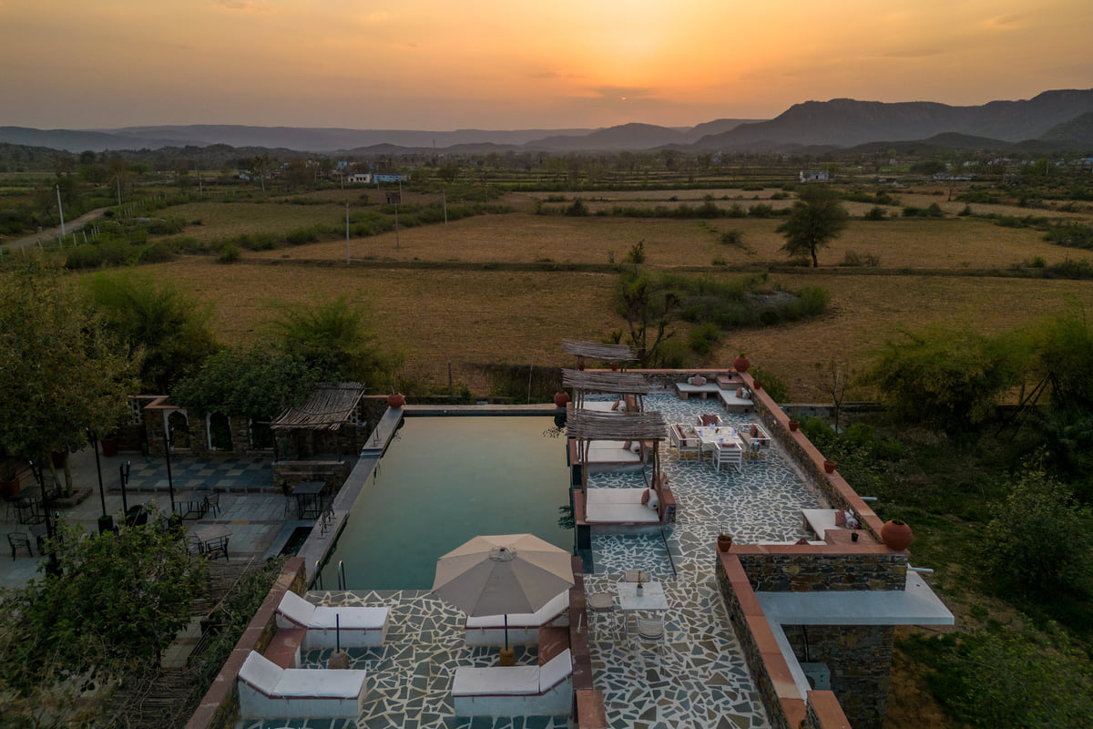 Pool and lounge seating at sunset overlooking the Aravallis