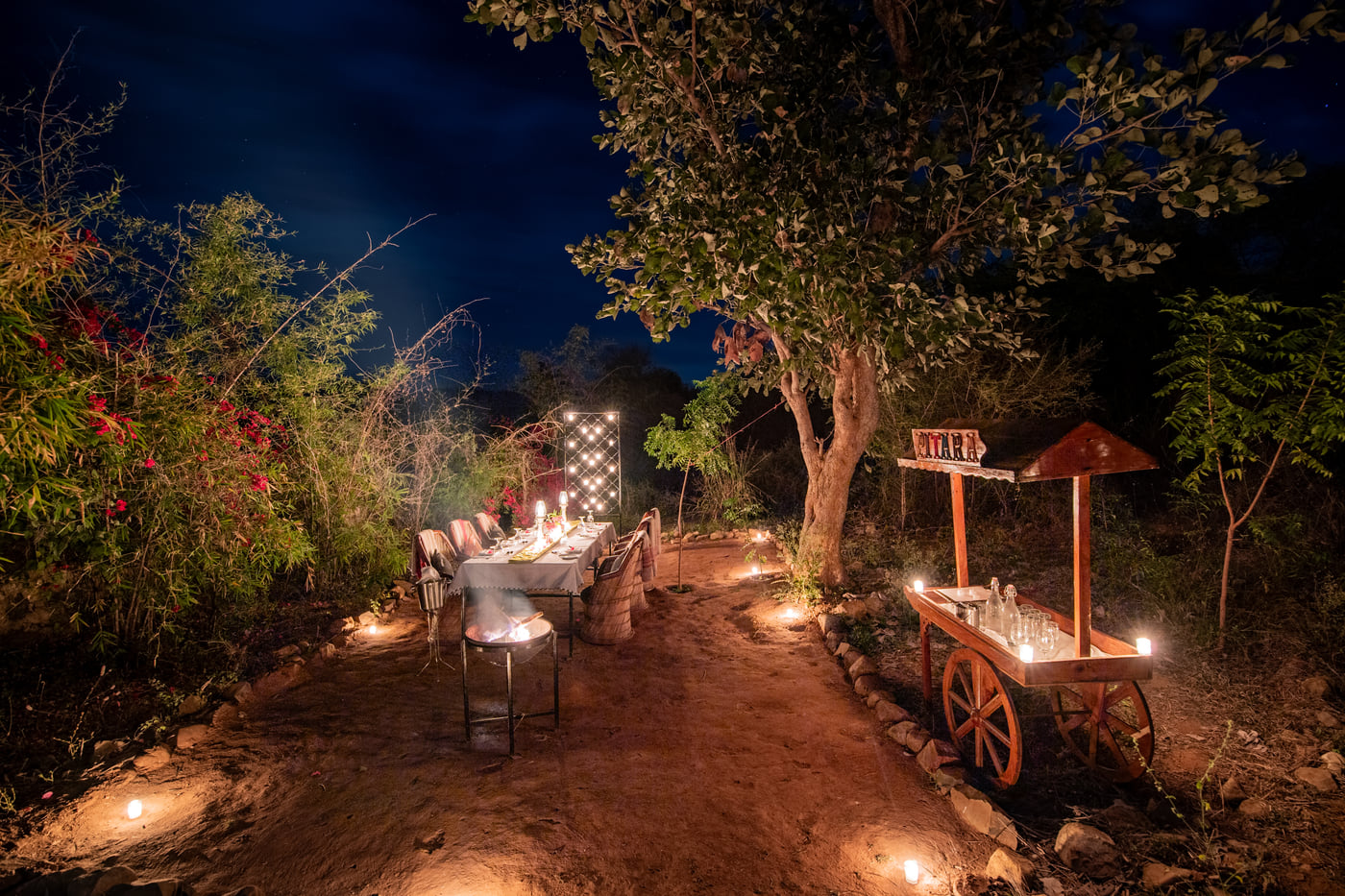 A candlelit table set outdoors under the night sky