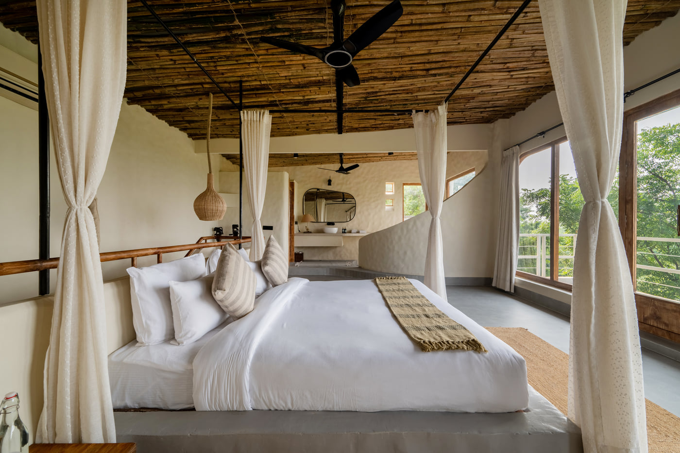 Bedroom with canopy bed, large windows, wooden ceiling, and serene outdoor views.