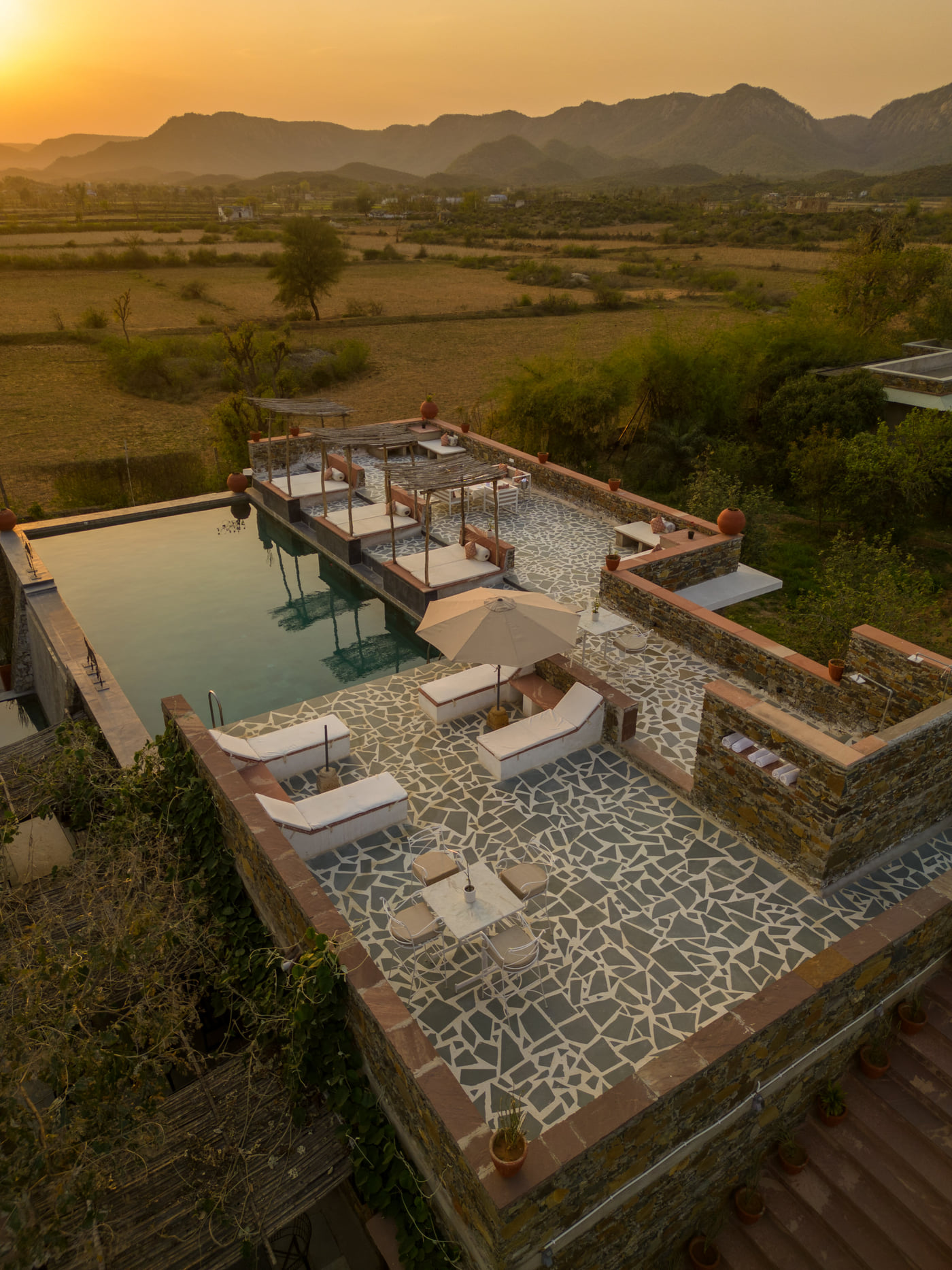 An aerial shot of a rooftop swimming pool seen during a sunset in the background