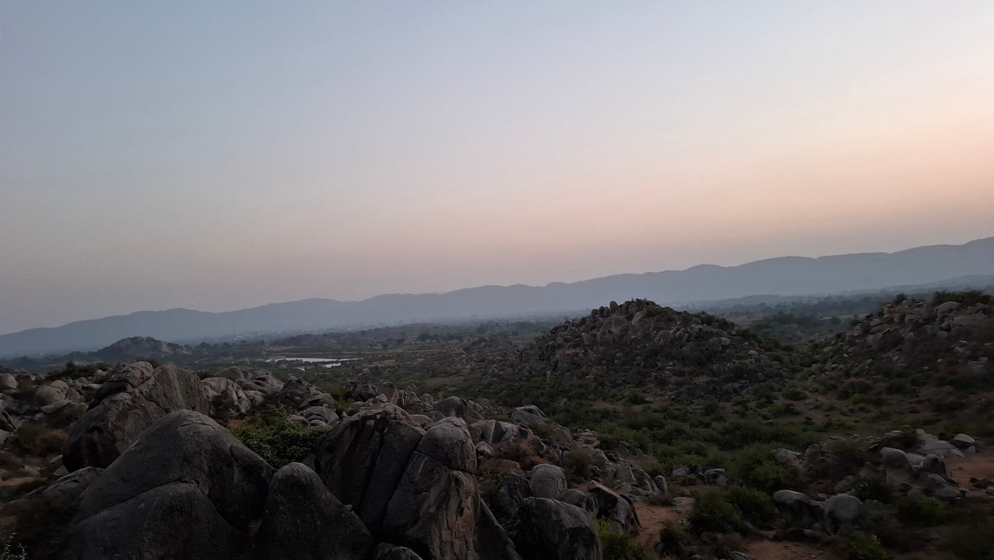 Aerial view of a land with huge rocks and visuals of lake at a far away distance