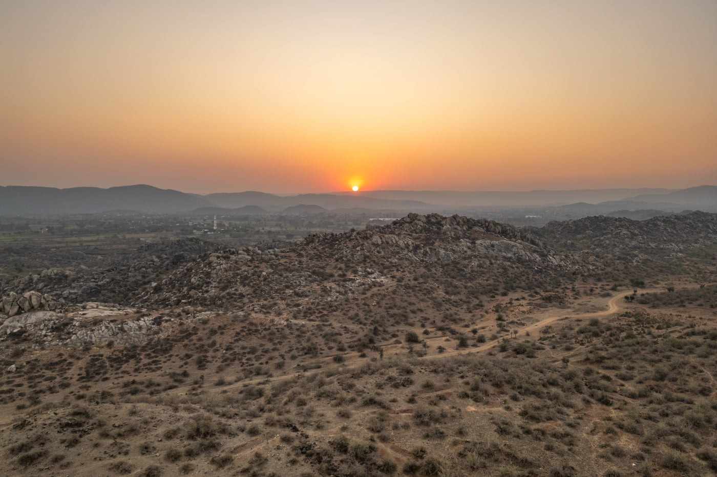 Sun setting over a barren stretch of rock and scrub