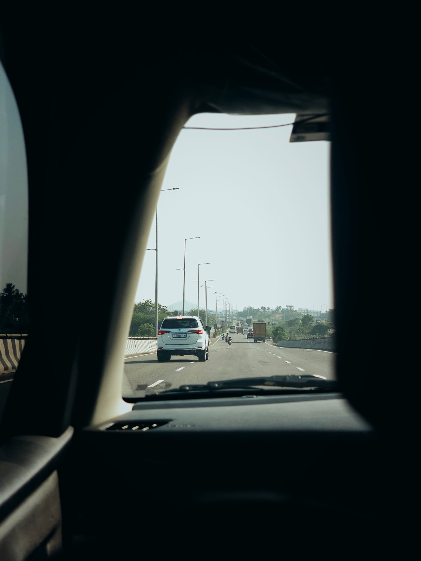 A close-up shot of the interiors of a car driving on a 6-lane highway on a bright day.