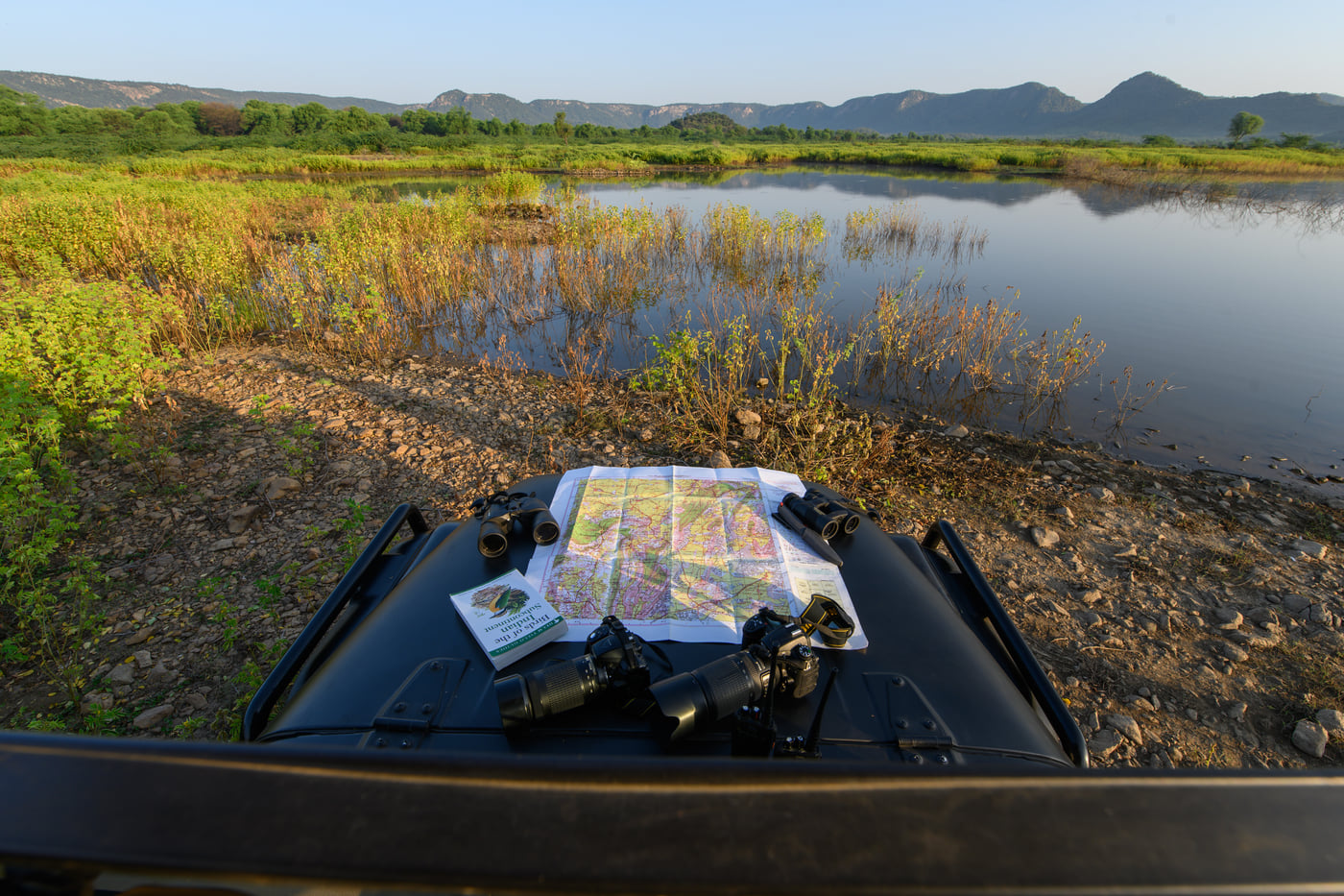 A map spread across the jeep bonnet at the water's edge