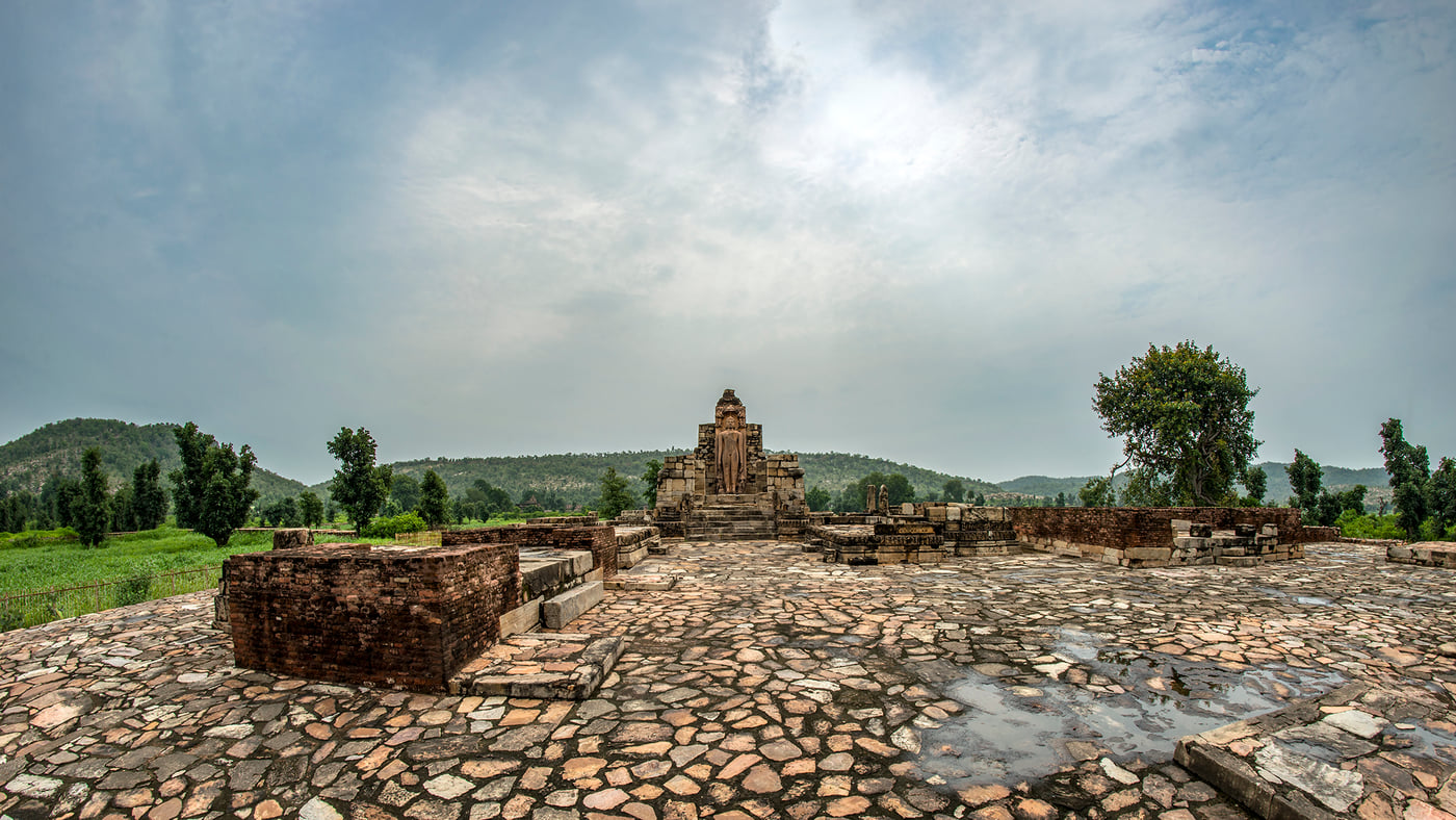 A stone temple standing alone on its paved platform under an open sky