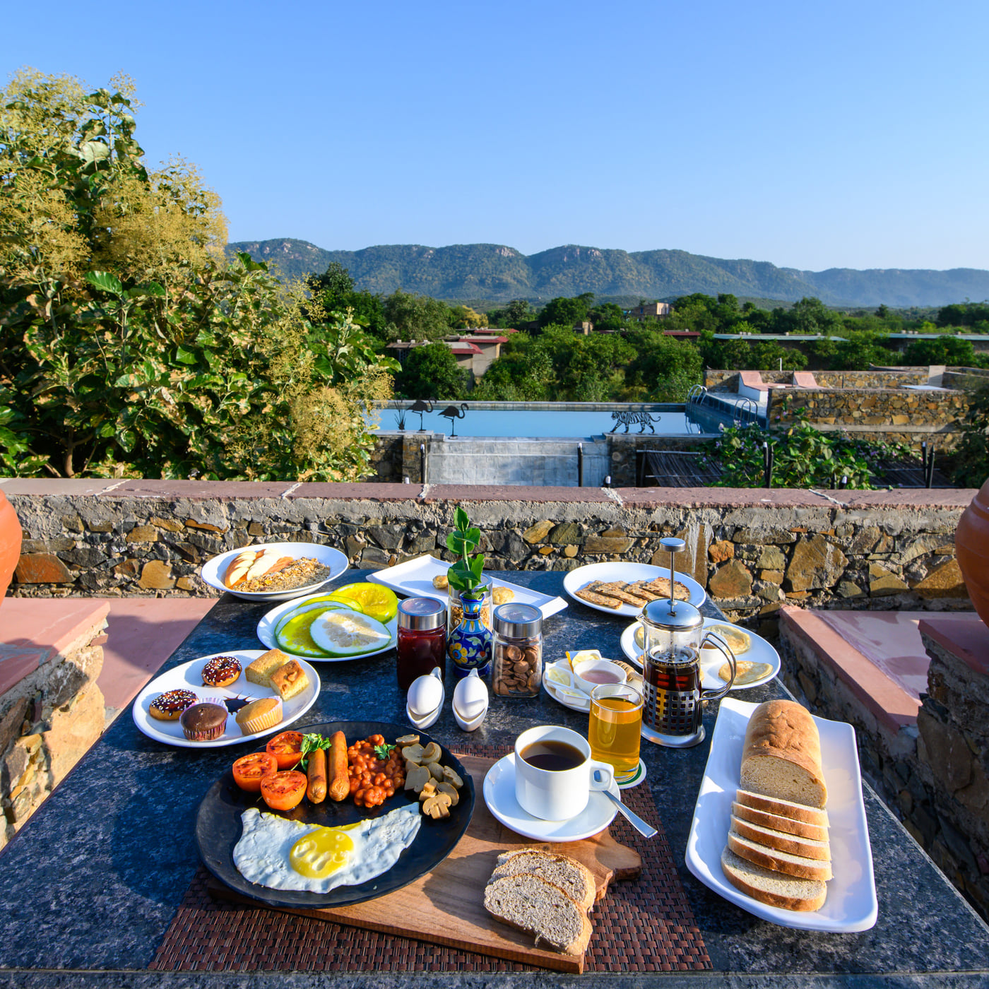 An outdoor dining setup with scenic views at Utsav Camp Sariska, offering a relaxed open-air meal surrounded by nature.