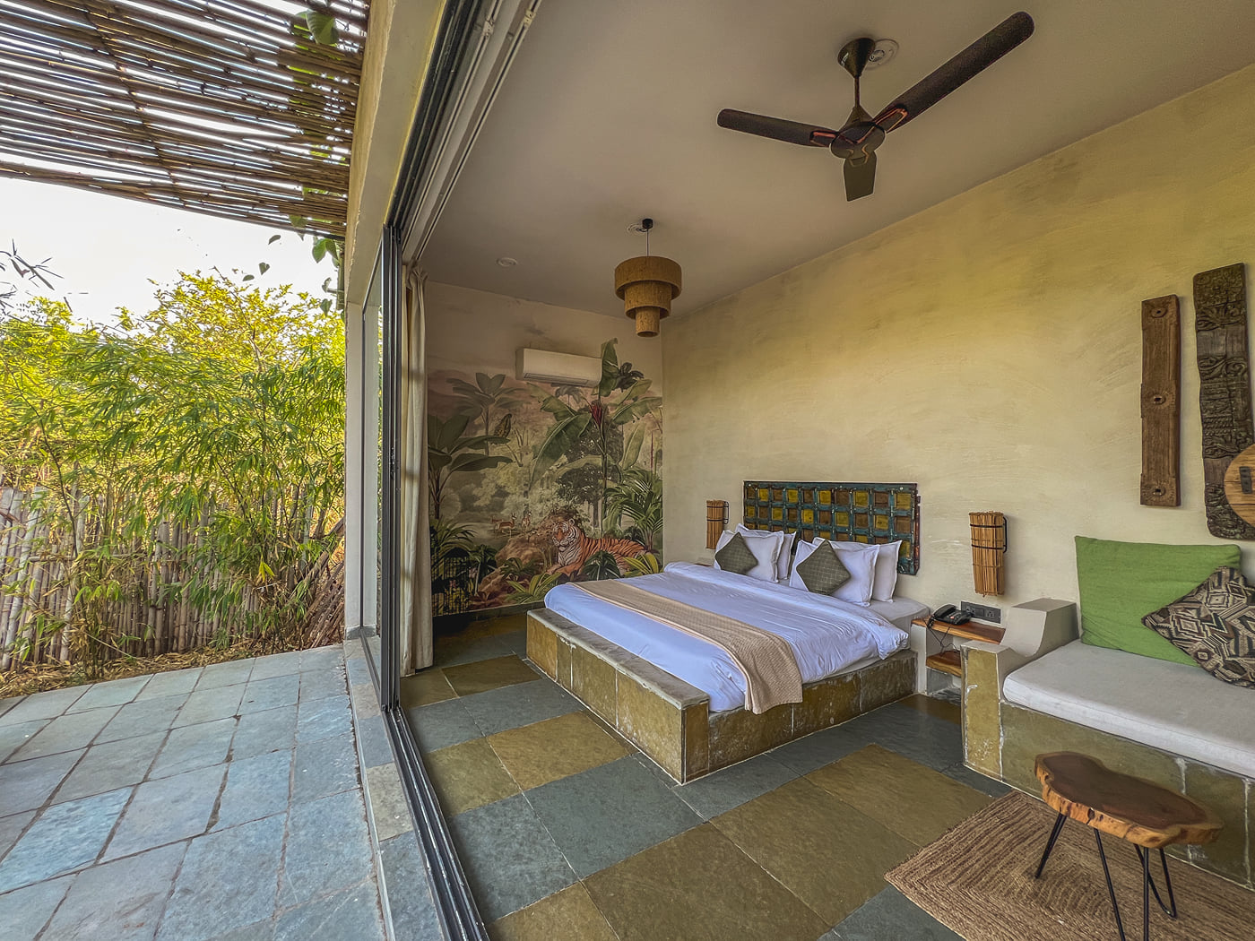 An image of the Stone Cabin with a large bed, a ceiling fan and comfortable furniture - Utsav Camp Sariska