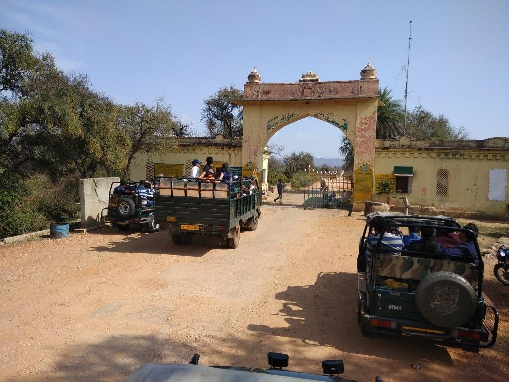 An overview of a entrance of Tehla safari gate with a canter and jeep in view near the entrance with many people on it near Utsav camp Sariska. A safari is possible during your day trip from Delhi to Sariska National Park.