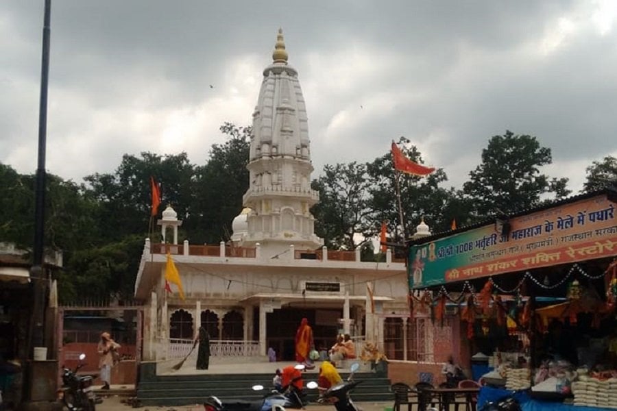 A temple with a tall tower stands against a cloudy sky.