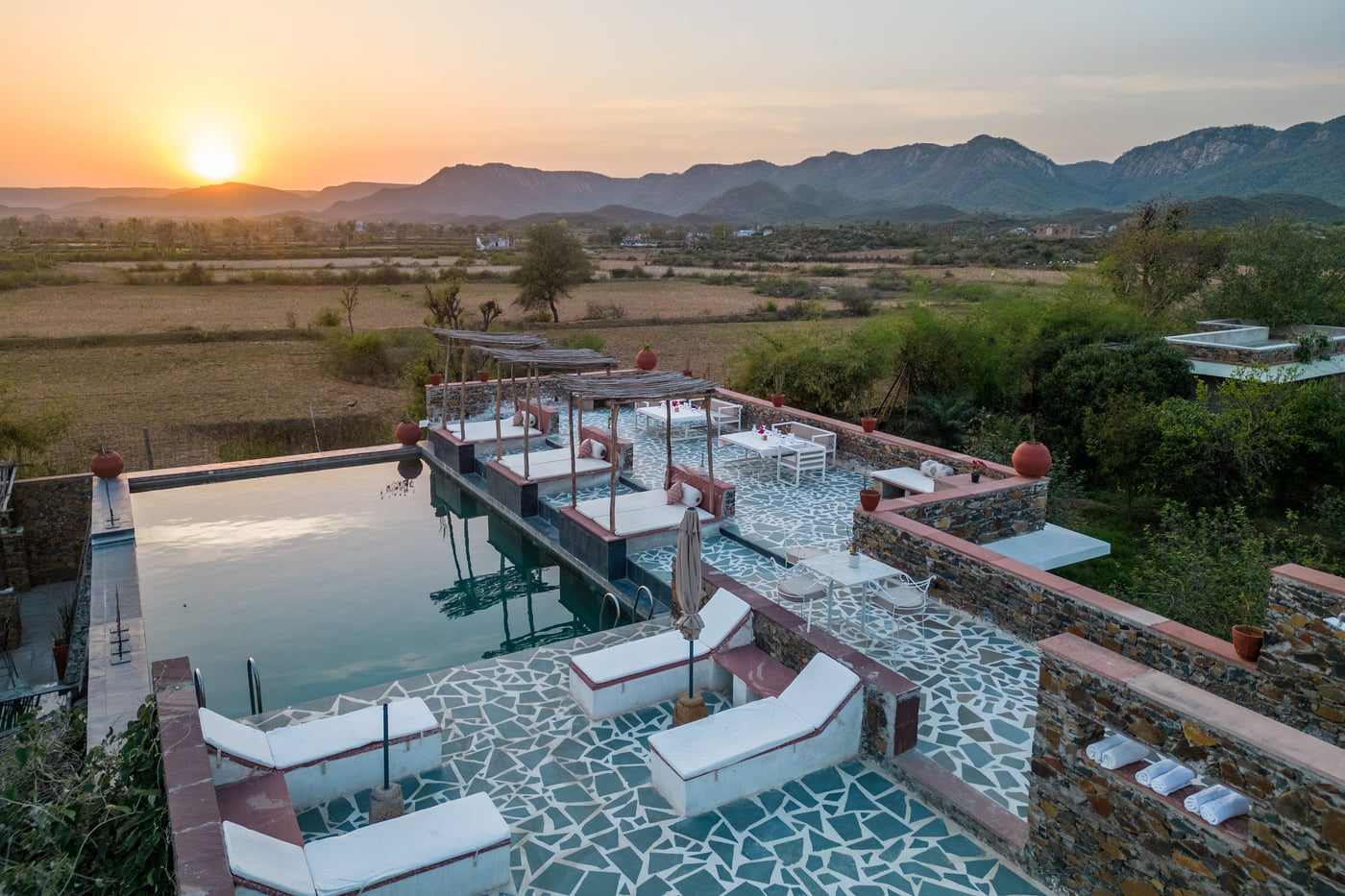 An aerial view image of a seating arrangement near the swimming pool in the open - Utsav Camp Sariska