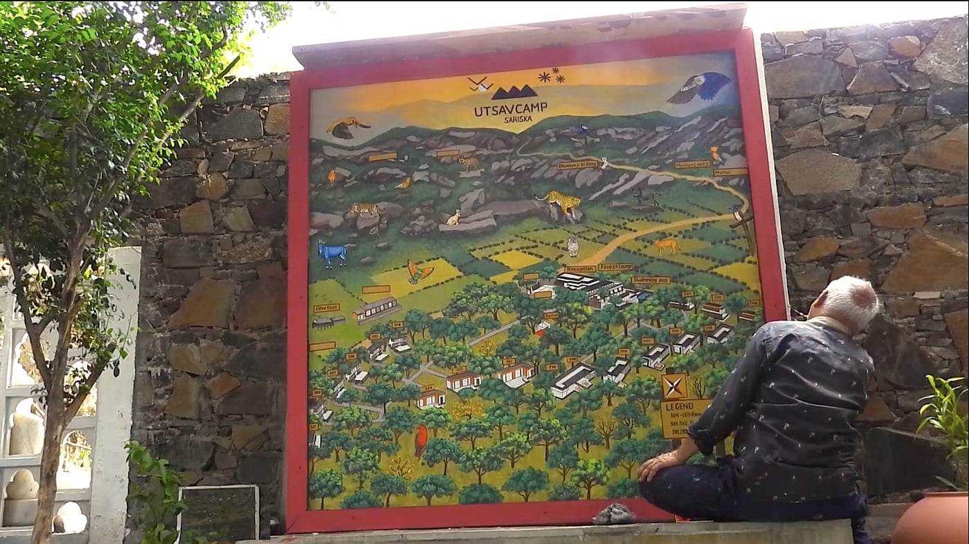 Artist painting the naturalist map at Utsav Camp Sariska on a large outdoor canvas.