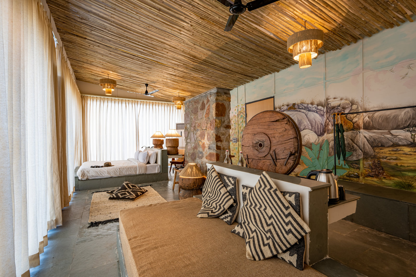 A guest room with a hand-painted mural, carved wood detail and cushioned seating