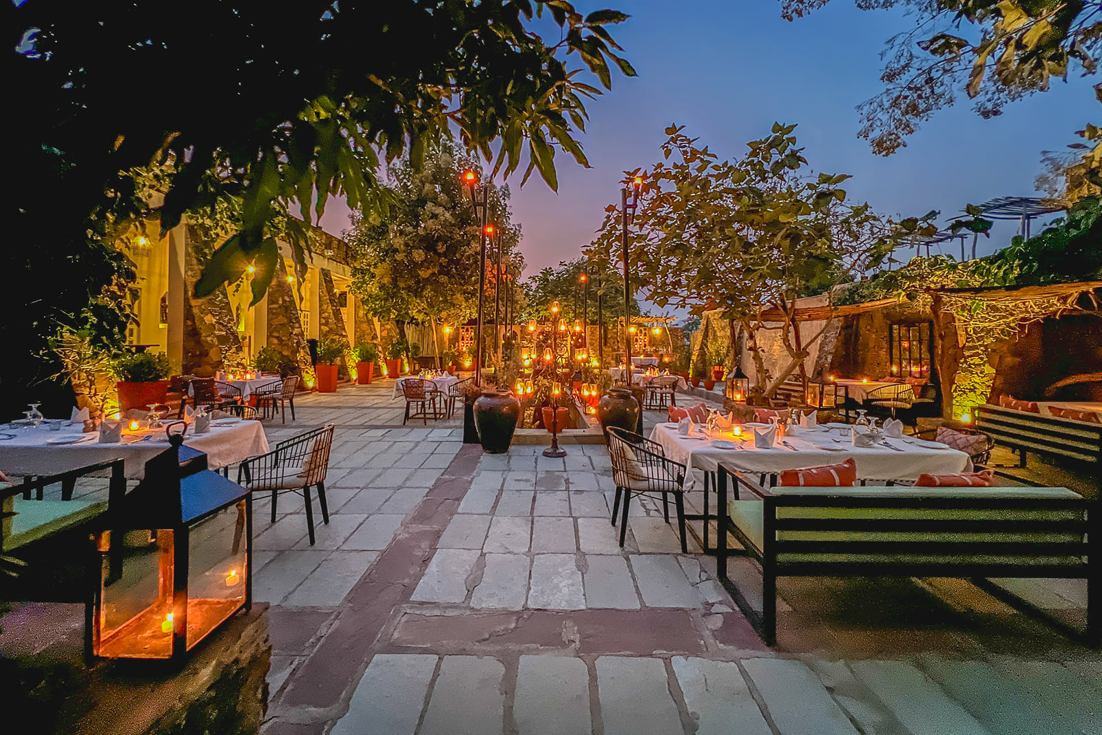 Lantern-lit outdoor tables in the camp's dining courtyard at dusk