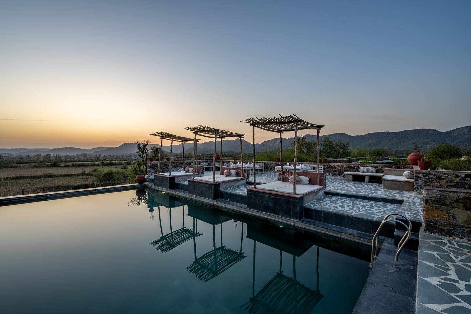 Shaded poolside loungers facing the hills at sunset