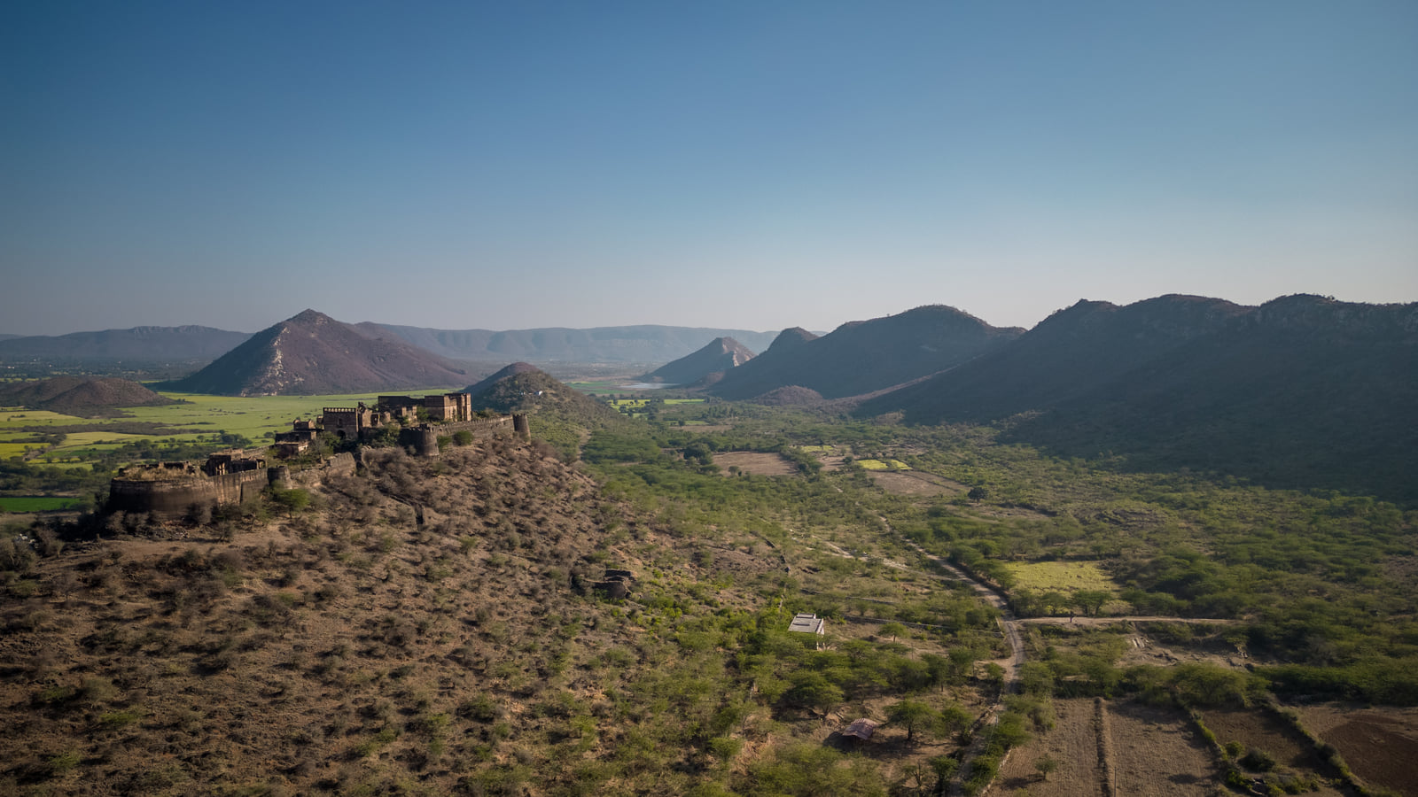 A ruined fort on a rocky spur above the fields and hills of Tehla, seen from the air